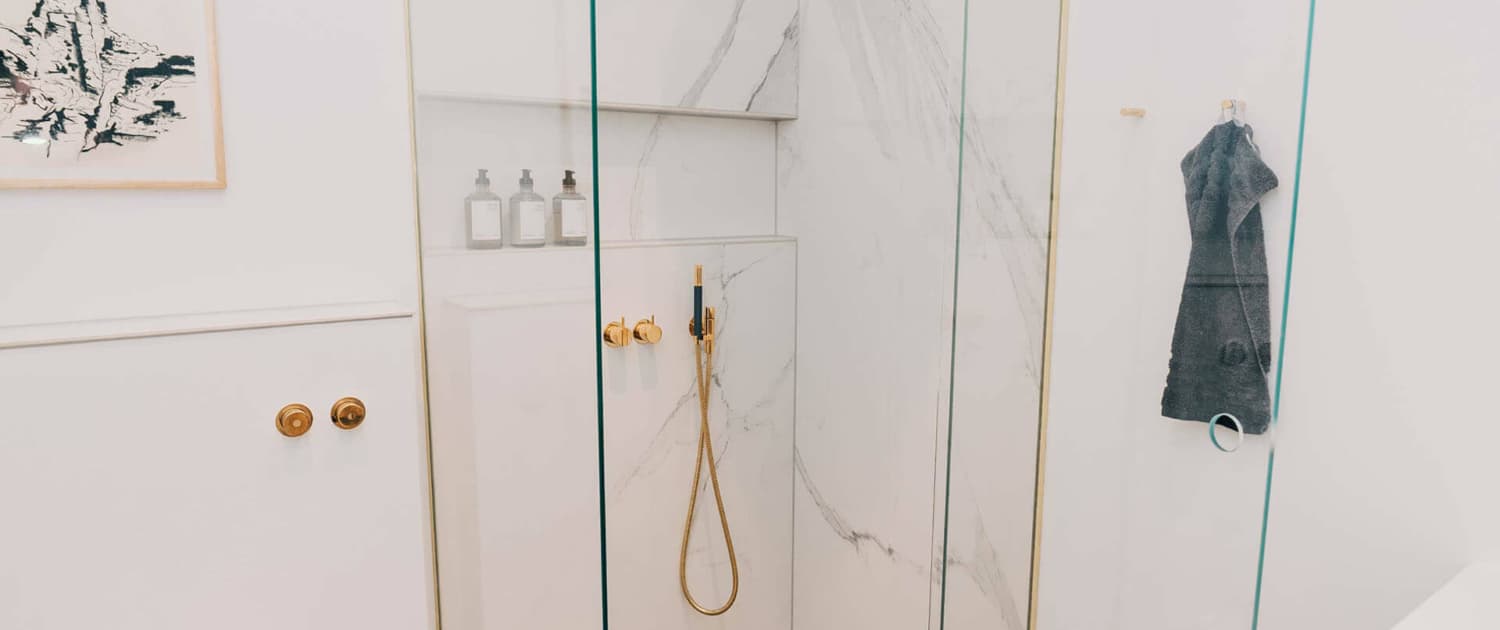 hvidt badeværelse med detaljer i guld og træ